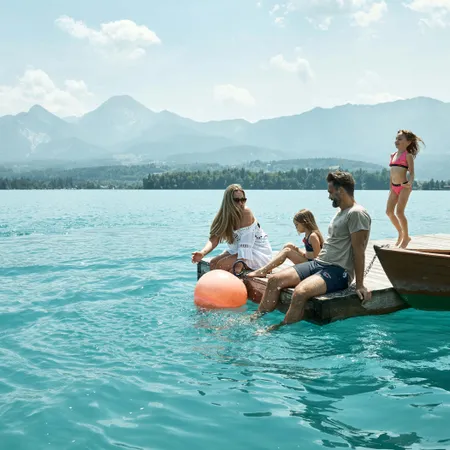 Family relaxing by turquoise lake with mountains in the background on a sunny day